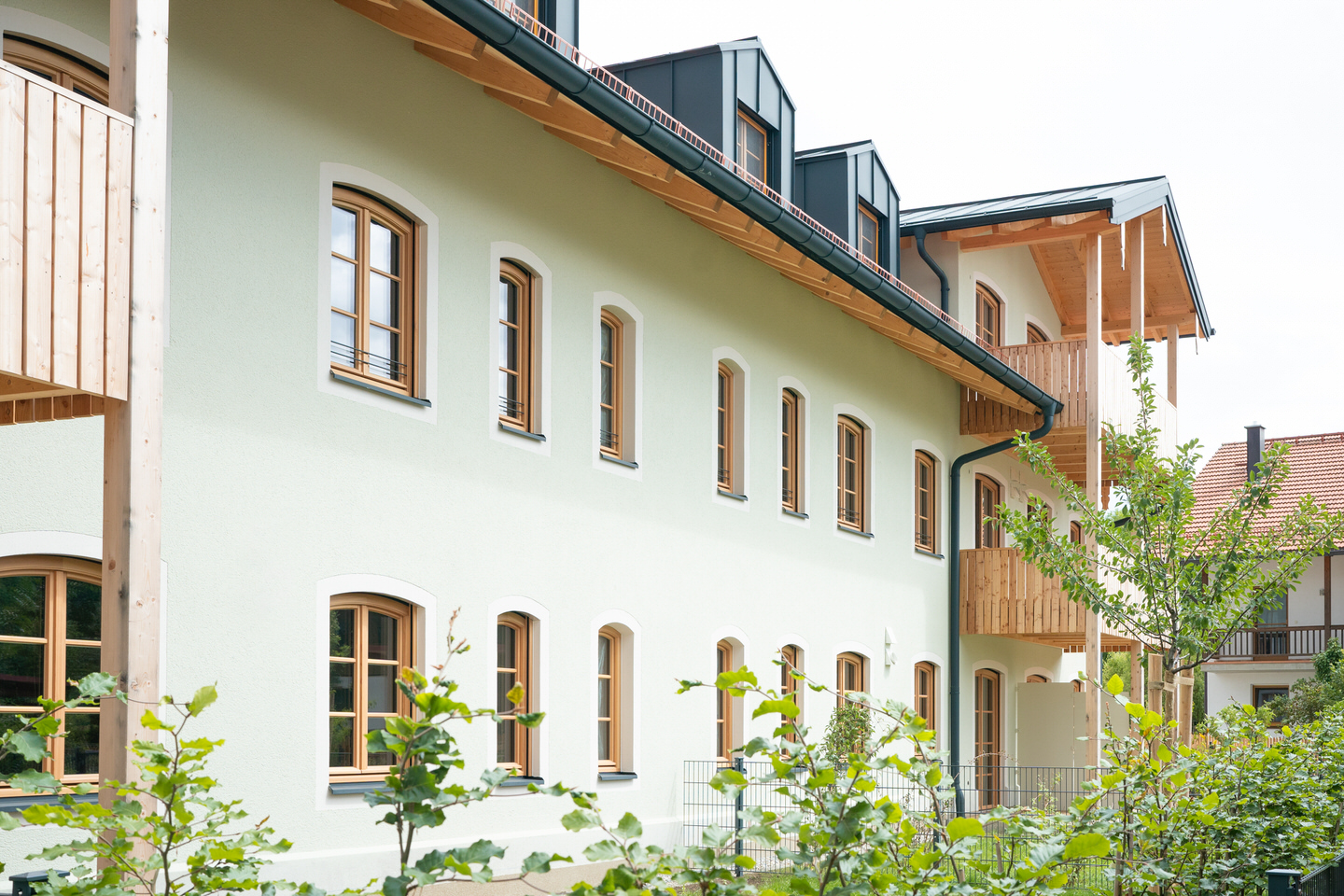 Lindgrüne Fassade in Kombi mit Lärchenholz
